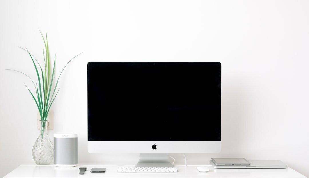 Modern office desk setup with monitor, keyboard and plant