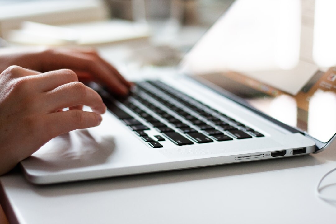Close-up of hands typing on a laptop keyboard